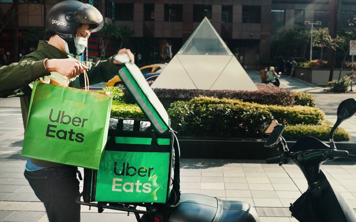 Eric handling Uber Eats delivery gear near a scooter in Taipei.
