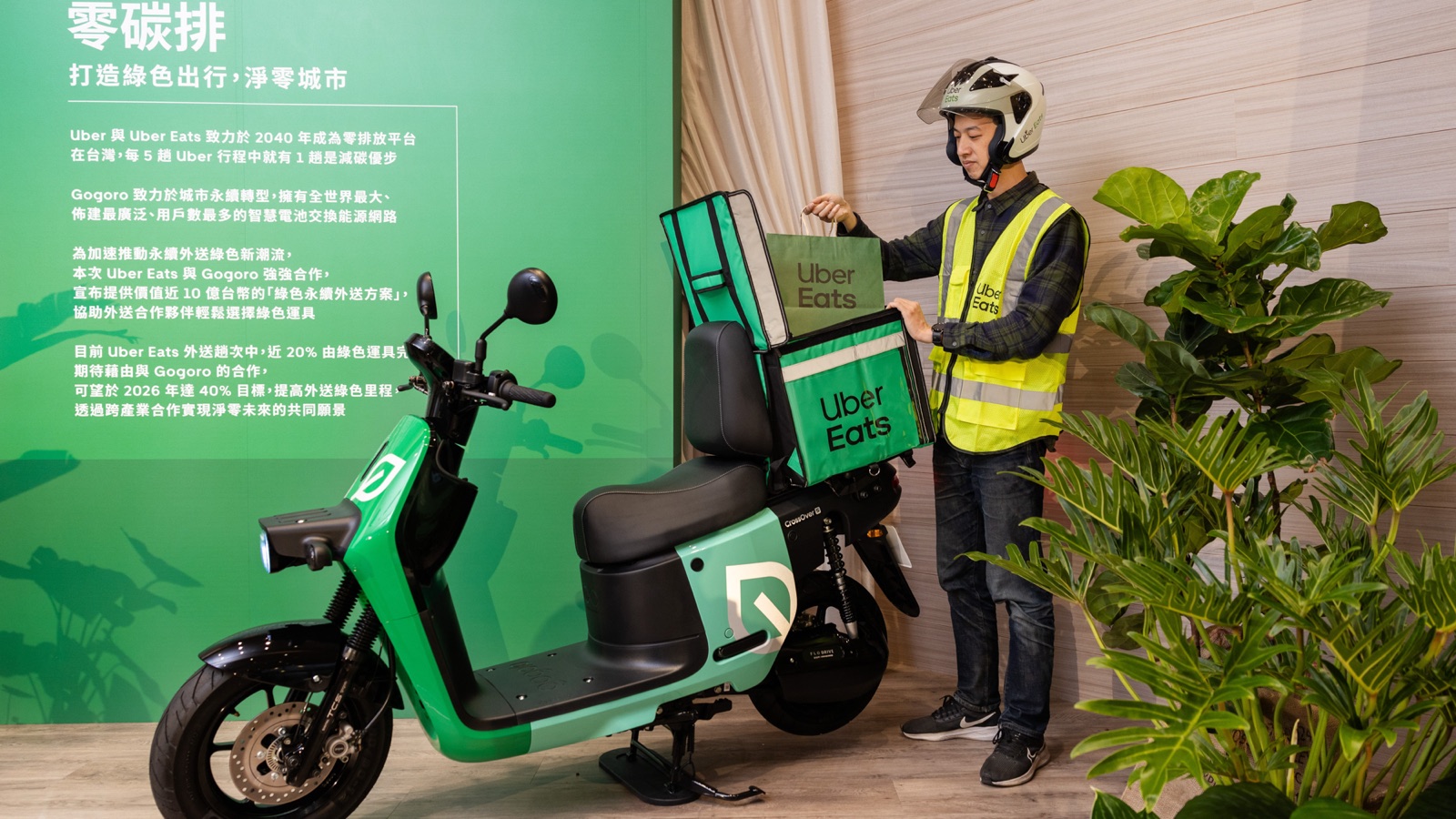 Eric standing with delivery gear and a Gogoro scooter at a green delivery event.