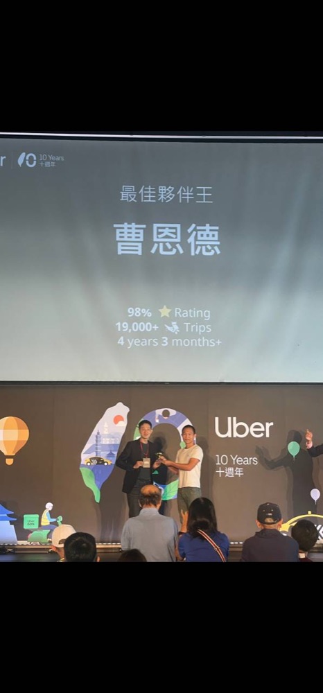 Eric on stage at an Uber 10 Years event with best partner recognition shown on screen.